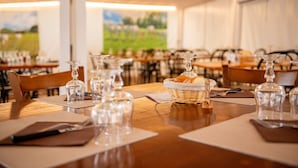 Un restaurant amb taules preparades per dinar, vidre transparent i una cistella de pa.