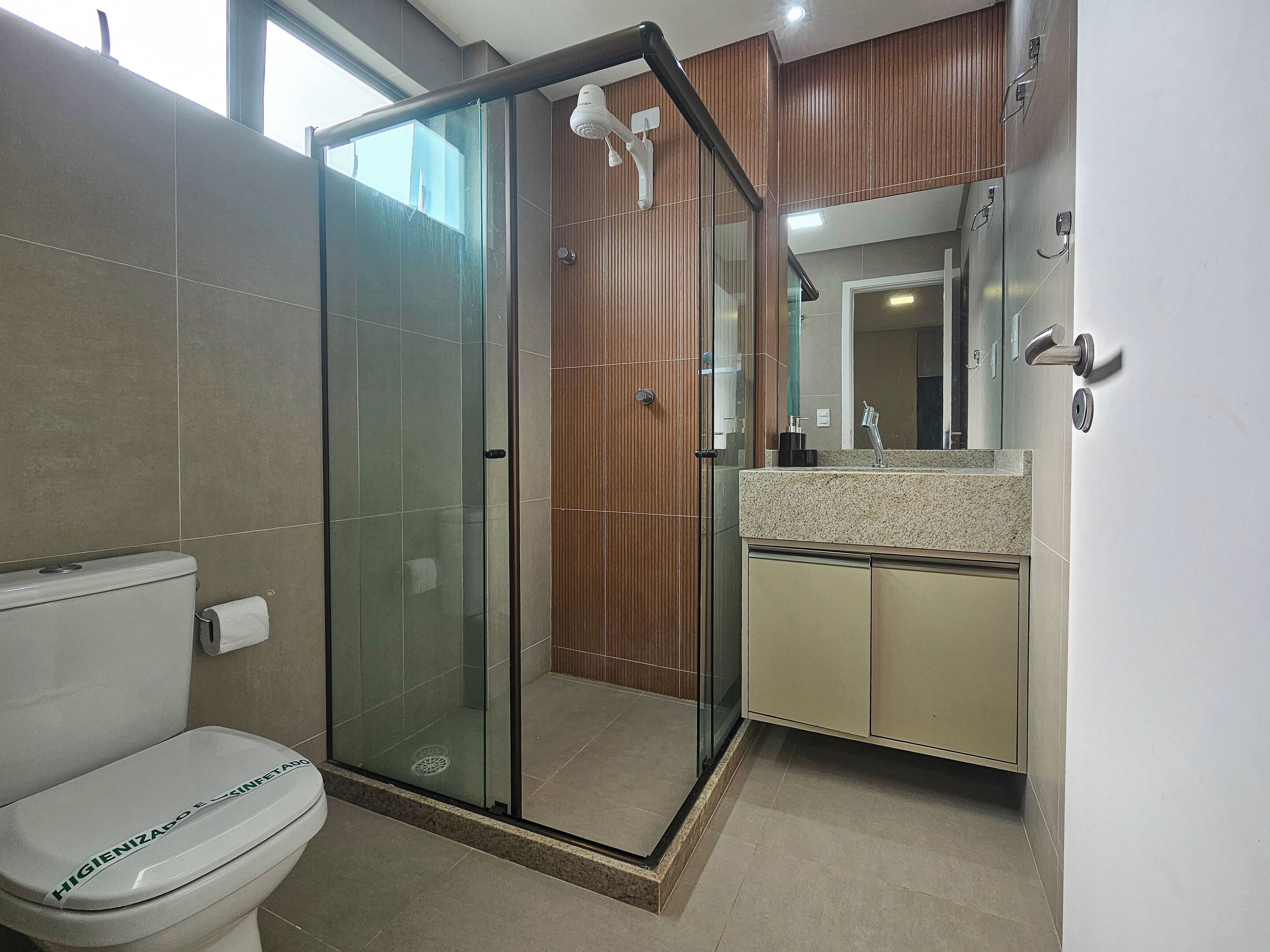 Een moderne badkamer met een douchecabine van glas, een toilet en een wastafel met spiegel.
