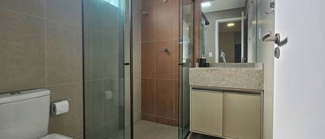 A modern bathroom with a glass-enclosed shower, a toilet, and a vanity with a mirror.
