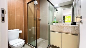 Un bagno moderno con doccia vetro, un water e un lavabo con piano in granito.