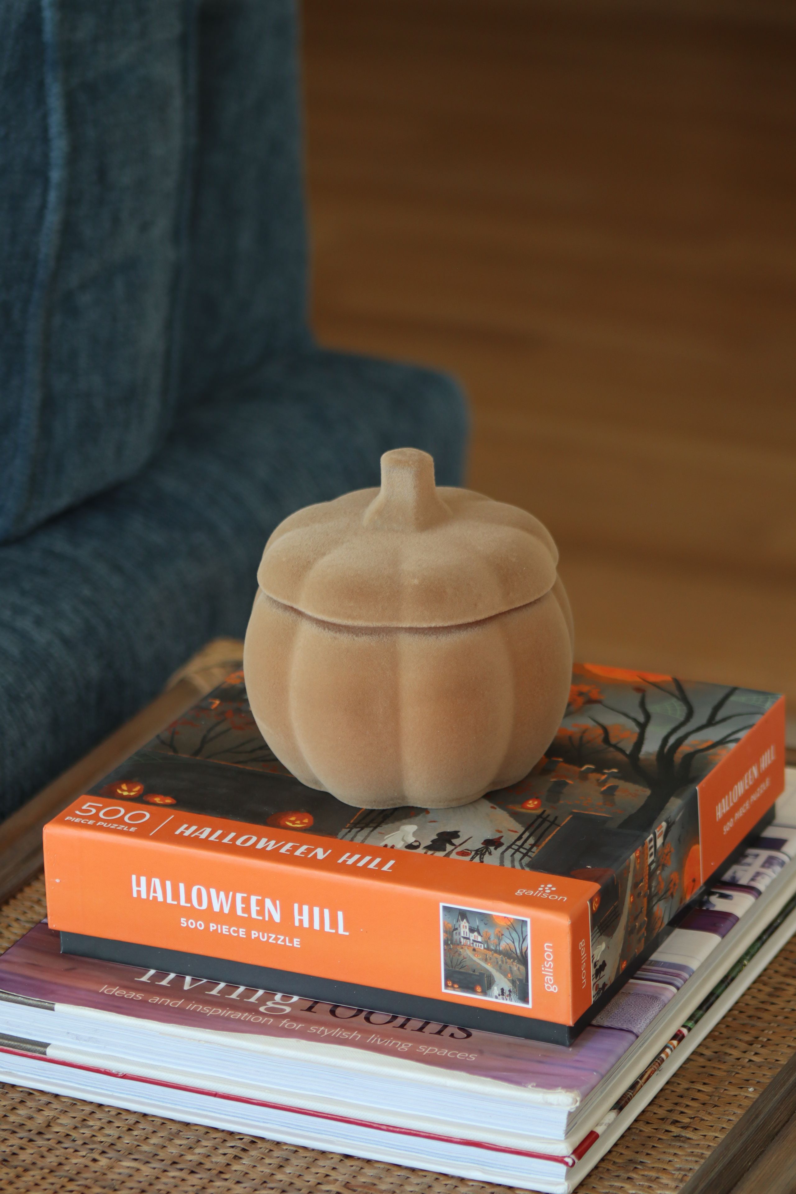 A pumpkin-shaped object on top of a book titled 'HALLOWEEN HILL' with a 500-piece puzzle.
