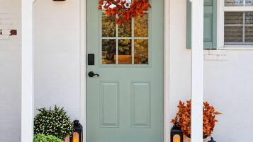 A front door with a wreath, a welcome mat, and two lanterns.