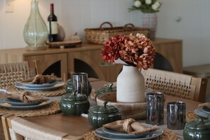 A dining table with a vase of flowers, plates, teapots, and glasses.
