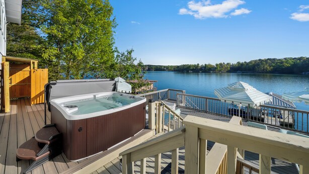 Een hottub op een terras met uitzicht op een meer en bomen.