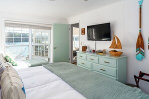 Une chambre à coucher avec un grand lit, une télévision, une commode et une vue sur l’extérieur.