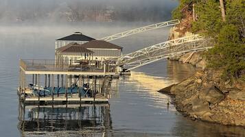 A pier extending into calm water with a gazebo-like structure and a bridge.