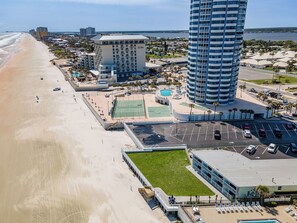 Ein Hotel direkt am Strand mit Pool, Tennisplätzen und einem Parkplatz.