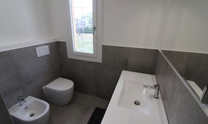 Een badkamer met toilet, bidet en wastafel.