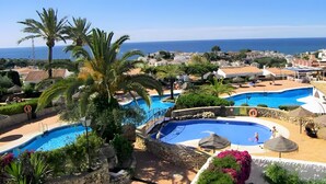 A resort with multiple swimming pools, palm trees, and a view of the sea. - Holiday Home 'Los Naranjos' with Shared Pool, Wi-Fi and Air Conditioning (Nerja)