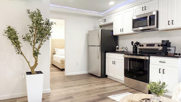 Een moderne keuken met witte kastjes, roestvrijstalen apparatuur en een houten vloer.