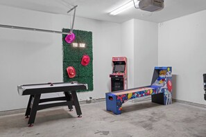 A billiards table, a pinball machine, and a neon sign in a room with white walls and a concrete floor. - Longhorn III | Walk to UT • Moody Center (Austin)
