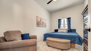 Un dormitorio con cama, sofá, un cuadro y cómoda.