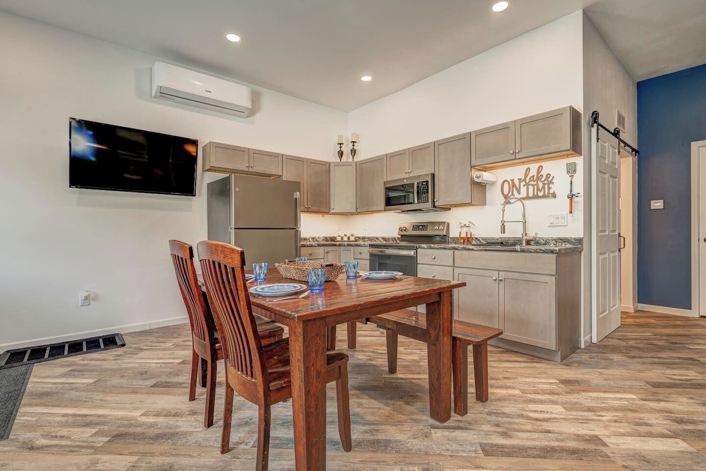 A modern kitchen with a dining area, built-in appliances, and a wall-mounted TV.