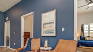Una habitación con pared azul, dos sillones de cuero, una mesita redonda y un cuadro.
