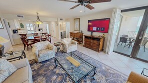 A living room with a sofa, armchairs, a coffee table, a TV, and a dining area with chairs and a table. - Recently Remodeled Mainsail 136 Stunning Beach Facing (Miramar Beach)