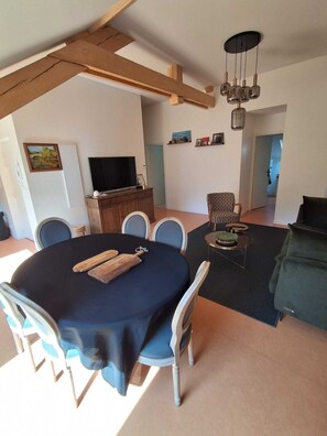 Un espace repas comprenant une table ronde, des chaises, un téléviseur et un canapé.