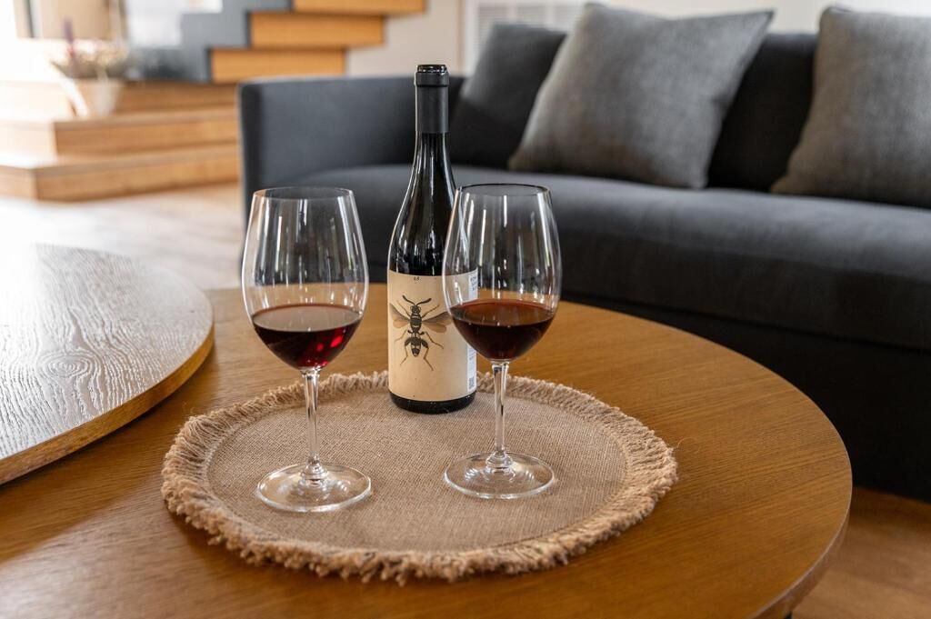 Une bouteille de vin sur une table, accompagnée de deux verres de vin rouge.