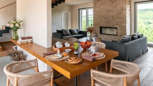 Un salon moderne avec un coin repas, un mur en pierre et de grandes fenêtres.