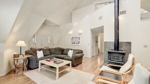 Ein Loft-Wohnzimmer mit hohen Decken, einem Kamin, einer Couch, einem Couchtisch und einem Sessel.