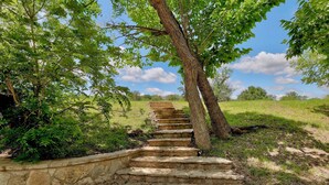 Eine steinerne Treppe führt bergauf, umgeben von Grün und Bäumen.