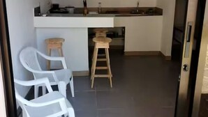 Una cocina moderna con una isla central, sillas blancas y un taburete de madera.