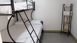 Habitación con literas, una estantería con toallas dobladas y una pared lisa.