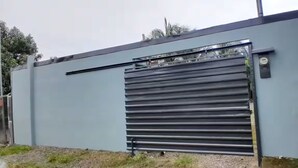 Un edificio moderno con una gran puerta metálica, techo plano y pared de concreto.