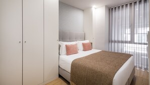 A bedroom with a bed, a wardrobe, and a window with curtains. - Ribeira Spacious Apartment for 6 (Oporto)