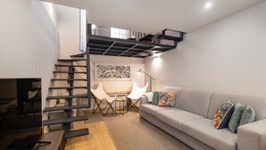 A modern living room with a staircase, a sofa, a coffee table, and a desk. - Ribeira Spacious Apartment for 6 (Oporto)