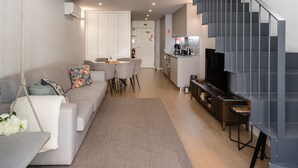 A modern living room with a sofa, a dining area, and a staircase. - Ribeira Large Apt for 6 (Oporto)