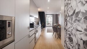 A modern kitchen with a built-in microwave, a coffee machine, and a dining area with a table and chairs. - Ribeira Large Apt for 6 (Oporto)