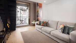 A living room with a sofa, a hanging chair, a fireplace, and a view of the outside. - Ribeira Large Apt for 6 (Oporto)