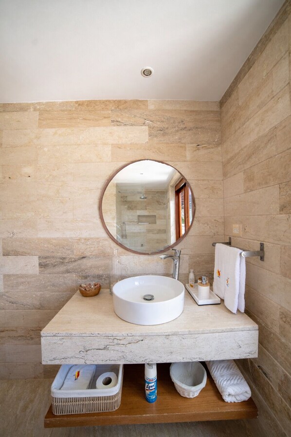 A bathroom with a round mirror, white sink, and a towel rack.