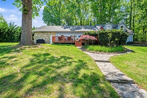 A house with a stone fireplace, a covered porch, and a stone pathway leading to the entrance. - Lake Norman cottage with stunning views (Mooresville)