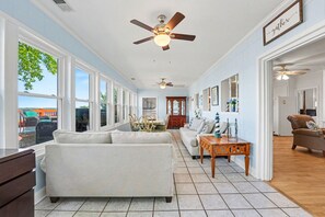 A spacious living room with large windows, a ceiling fan, and a view of the outdoors. - Lake Norman cottage with stunning views (Mooresville)