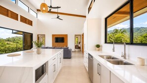 Una cocina moderna con una isla grande, electrodomésticos integrados y vistas a exuberante vegetación.