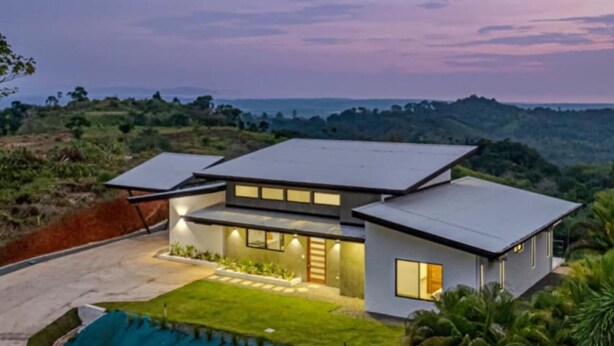 Una casa moderna con techo plano, ventanas grandes y césped cuidado.