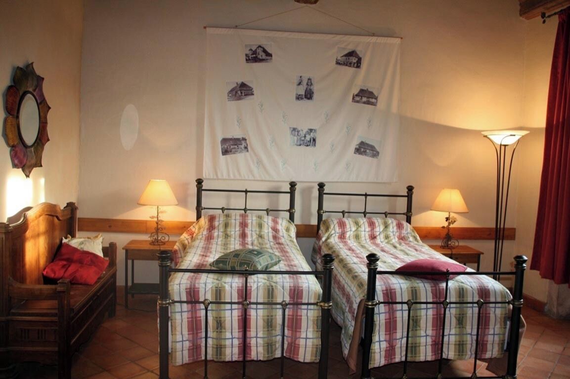 Een kamer met twee bedden, een houten stoel, een tafeltje en een wandtapijt.
