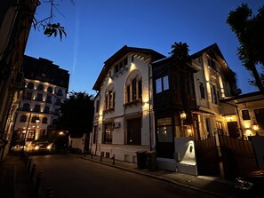 A historic building with arched windows and a balcony, surrounded by other buildings. - Cismigiu Superior Apartment (Bucharest)