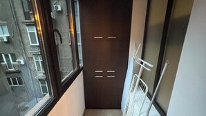 Ein schmaler Flur mit einem Fenster an einer Seite, einer Tür mit Griff und einem weißen Heizkörper an der anderen.