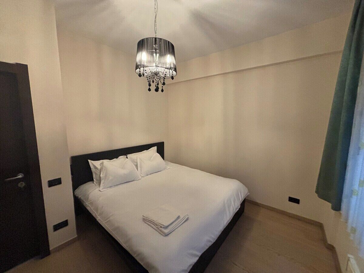 A hotel room with a bed, a chandelier, and a door.