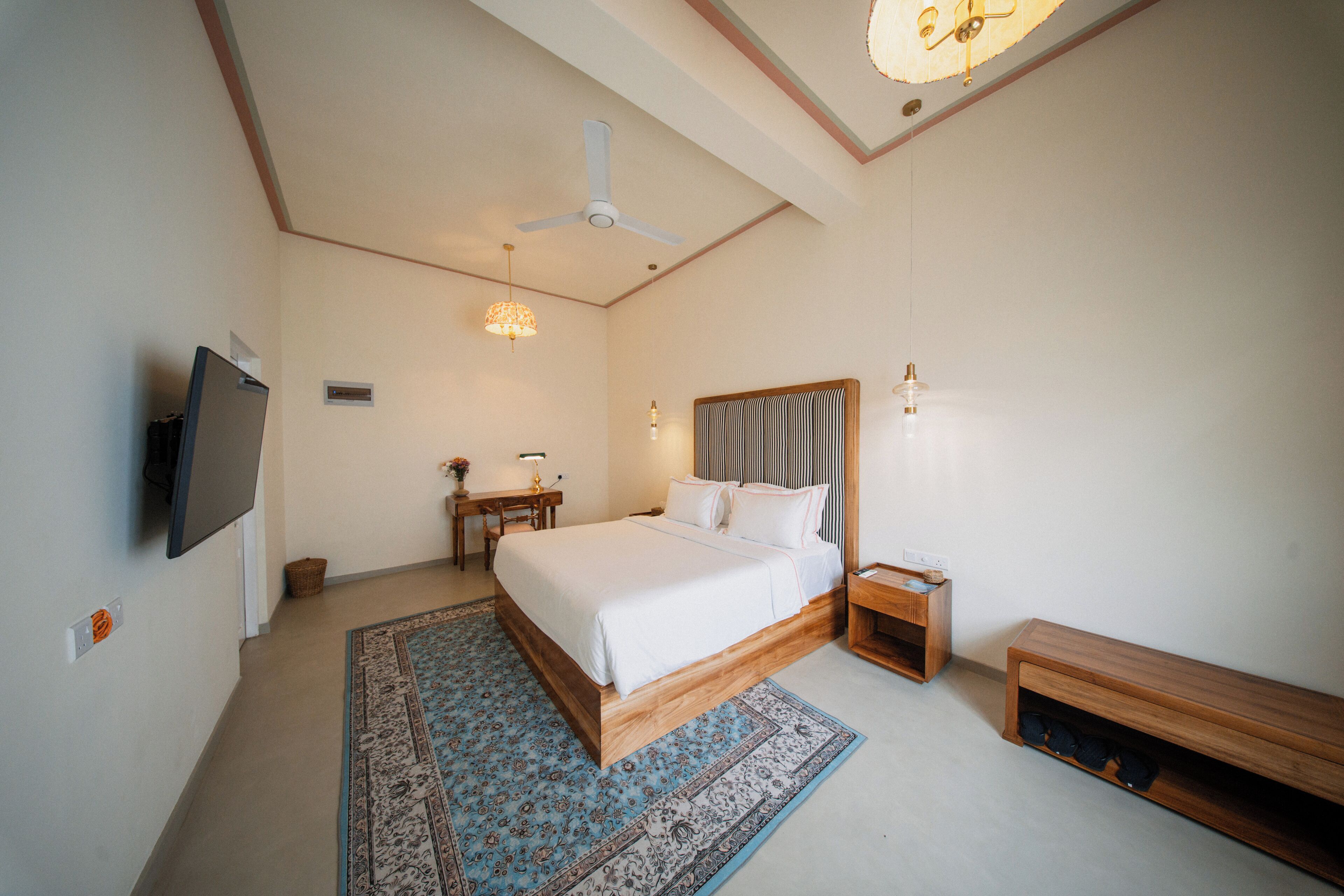 A bedroom with a bed, bedside tables, a TV, a ceiling fan, and a rug.