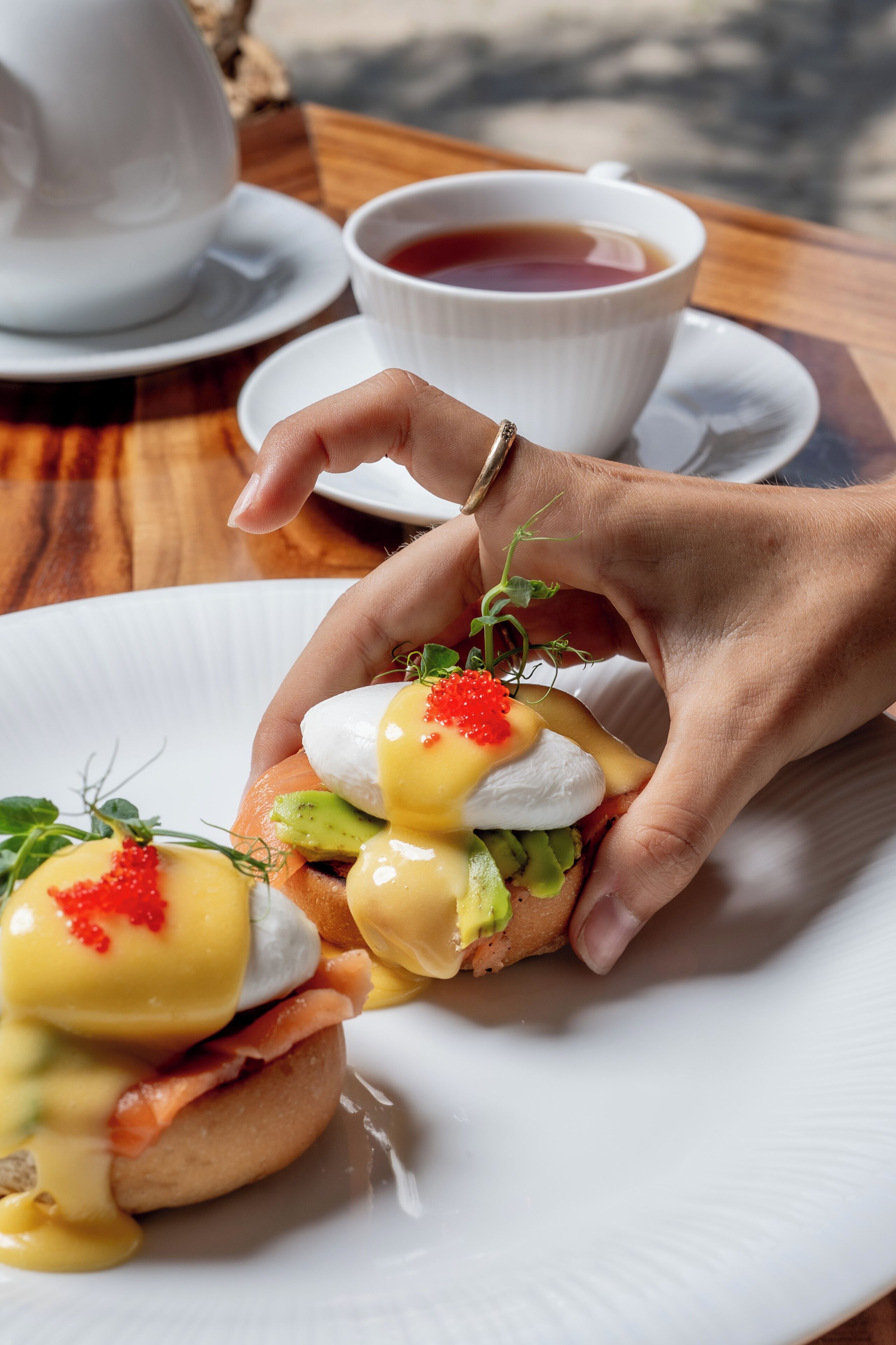 A breakfast setting with a plate of eggs benedict and a cup of tea.