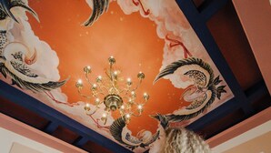 A woman in a room with a decorative ceiling, columns, and a chandelier. - Padmaraga (Galle)