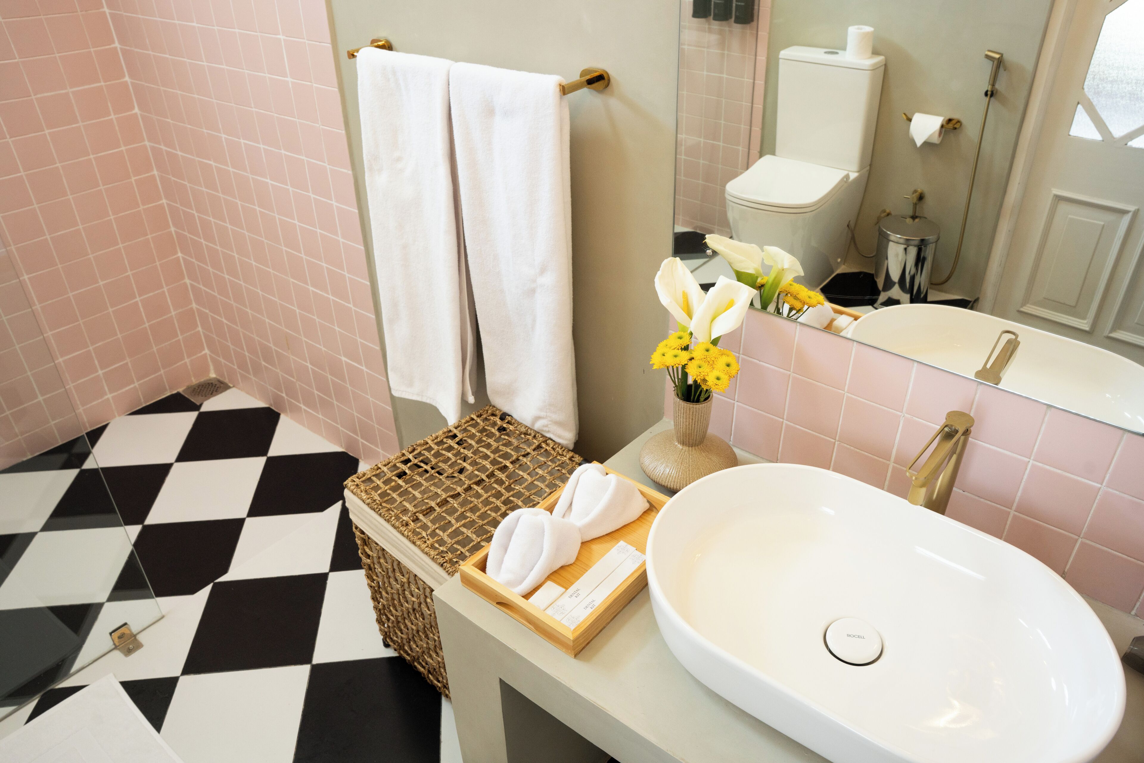 A bathroom with a checkered floor, a white sink, a mirror, and towels on a tray.