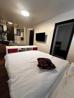 Ein Hotelzimmer mit Bett, Wandfernseher, Schreibtisch und Stuhl.