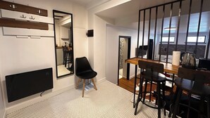 A modern kitchen with a large mirror, a dining area with wooden tables and black chairs, and a black TV mounted on the wall. - Cismigiu Ground Floor w Garden View Apartment (Bucharest)