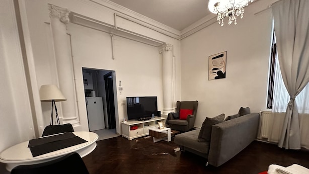 Una sala de estar moderna con un sofá, televisor y una pequeña mesa.