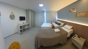 A hotel room with two beds, a desk, a chair, a TV, and a small plant. - Porto Baobas Vista Mar 102 By LP (Ipojuca)