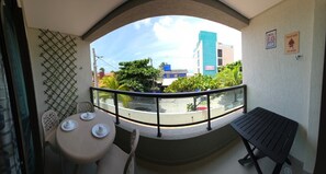 Ein Balkon mit Tisch und Stühlen und Blick auf Gebäude, sowie ein Schild an der Wand.